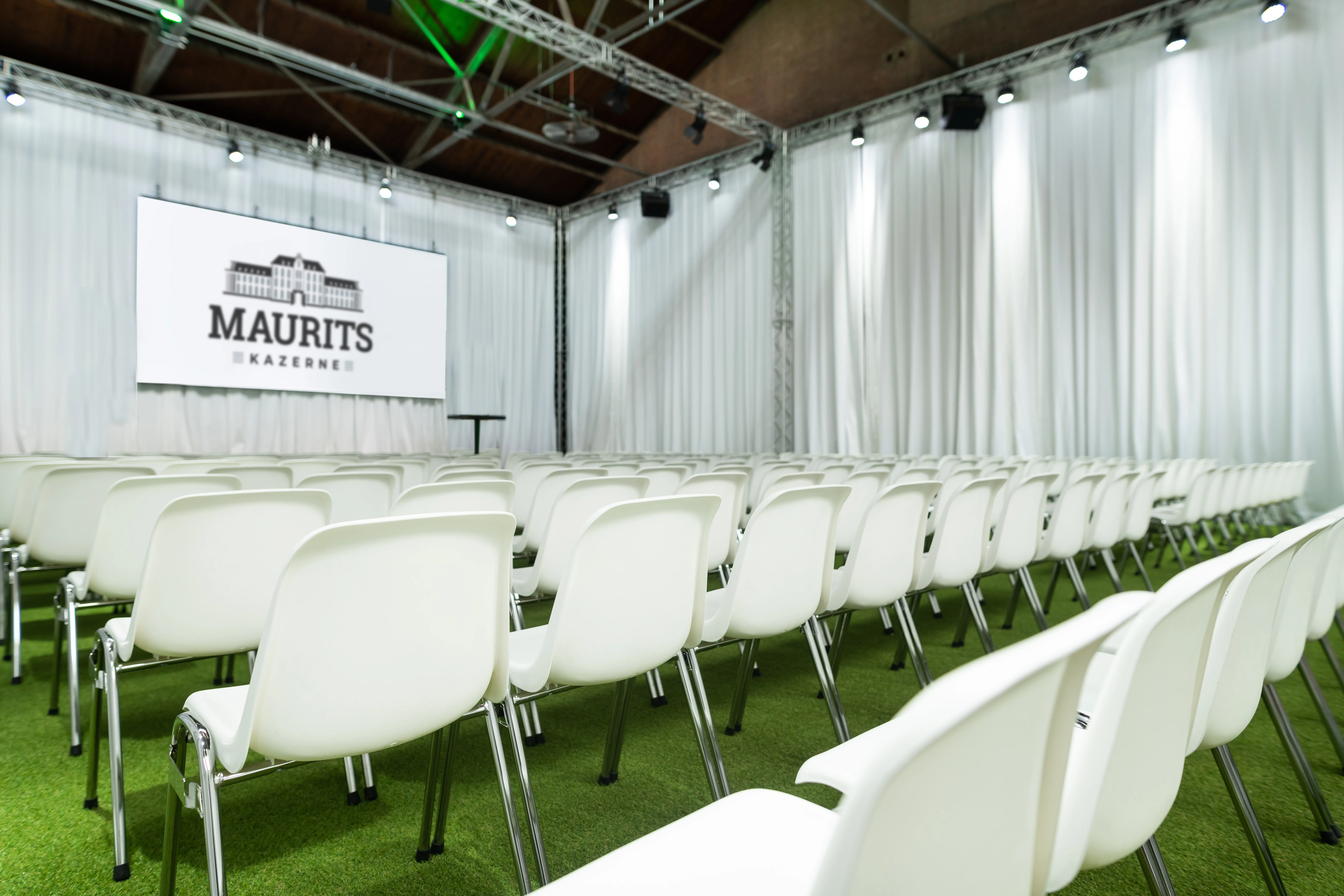 Congreszaal klaar voor zakelijk event met stoelen en scherm in de Mauritskazerne