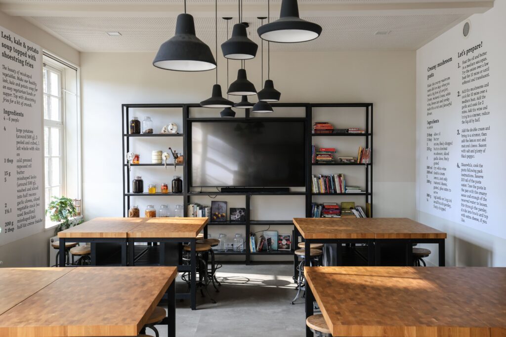 Workshopruimte met houten tafels in cabaretopstelling en scherm in de Mauritskazerne