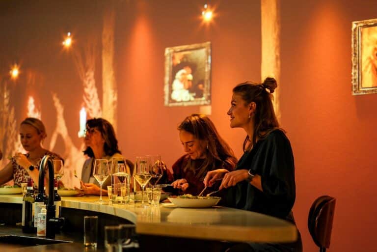Gasten genieten van een culinair diner in een sfeervol restaurant met warme verlichting en moderne inrichting.